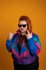 Plus size woman in sunglasses showing rock signs isolated on yellow background