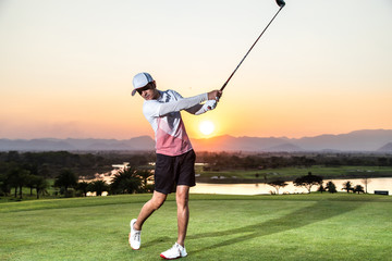 Professinal golf player on golf course. Pro golfer taking a shot at the sunset