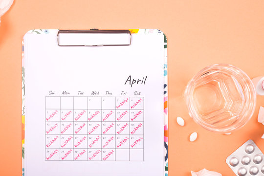 April calendar that says allergy. The concept of allergic tinitis and its treatment with pills. Top view, flat lay.