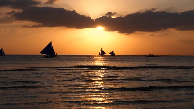 Beautiful orange sunset at Boracay Island of Philippines with silhouette of sailing boats 60fps