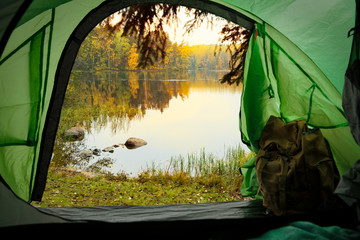 View from inside a tourist tent with backpack. Beautiful Scandinavian landscape of forest and lake....