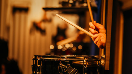 The drummer plays the drums. Beautiful blue  background, with rays of light. Beautiful  lighting. The process of playing a musical instrument. Close-up photo.