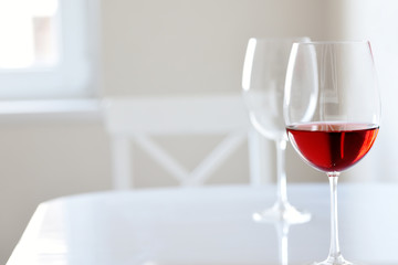 Glass with red wine on a white table in a white interior. Contrast photo in a stylish white room. Minimalism