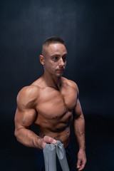 Fototapeta na wymiar Muscular man doing calisthenic exercise with power band isolated on the black background