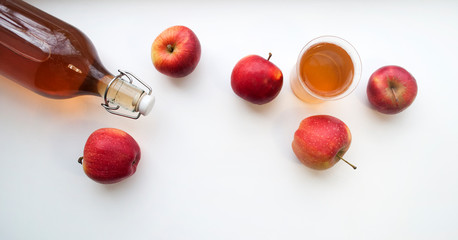 Top view of a bottle and glass with natural apple juice  on white, banner.  Homemade apple juice.