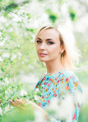 Romantic portrait of a beautiful woman in a Park on a background of blooming cherry trees. Tender photo with a beautiful girl in the spring garden