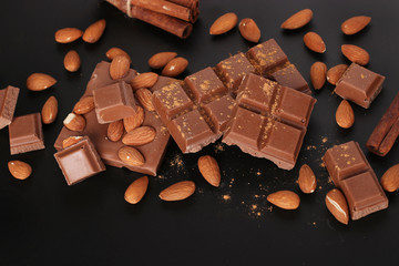 Chocolate with almonds and cinnamon on a dark background close-up