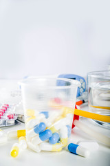 Pharmaceutical medicine pills concept, Assorted various pills, tablets and capsules with medical syringes, thermometer and water glass, copy space mockup, flatlay