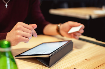 Shot of an unrecognizable man doing online shopping on his digital tablet and holding his credit card