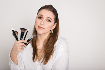 Makeup artist with brushes on white background.