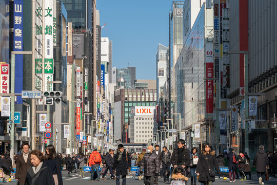 TOKYO, JAPAN - FEB 2019 : Undefined Japanese and Foreign tourists are Walking across the crosswalk around Ginza Wako and Ginza Mitsukoshi upmarket on Febuary 17, 2019, Tokyo, Japan.