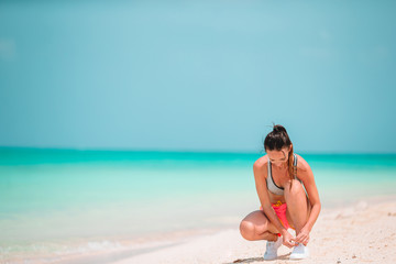 Fototapeta na wymiar Fit young woman on the tropical beach in sportswear