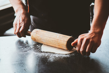 Man rolling dough on kitchen table