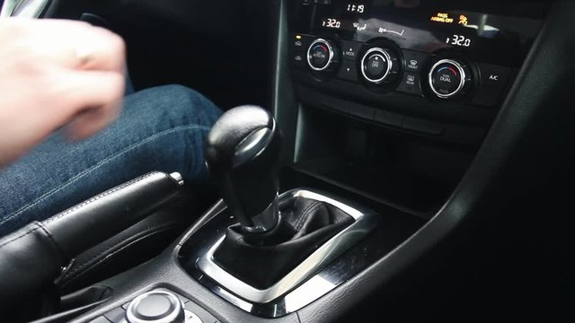 Female hand shifts gears. Automatic transmission, automatic gear shift, is moved from P to D. Park to Drive
