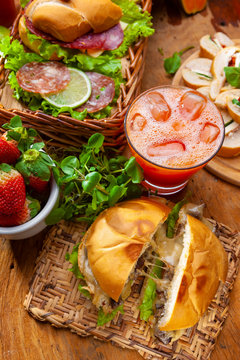 sandu&iacute;che de carne com queijo e alface em mesa com sucos e frutas