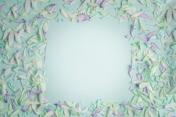 spring square frame with flower petals in white and green shades, on a light green matte background. flat bookmark, top view.