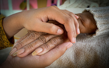 ็Hands of an old woman and granddaughter and caring for the elderly in the family