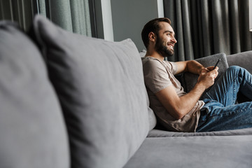 Cheerful happy young positive man using mobile phone.