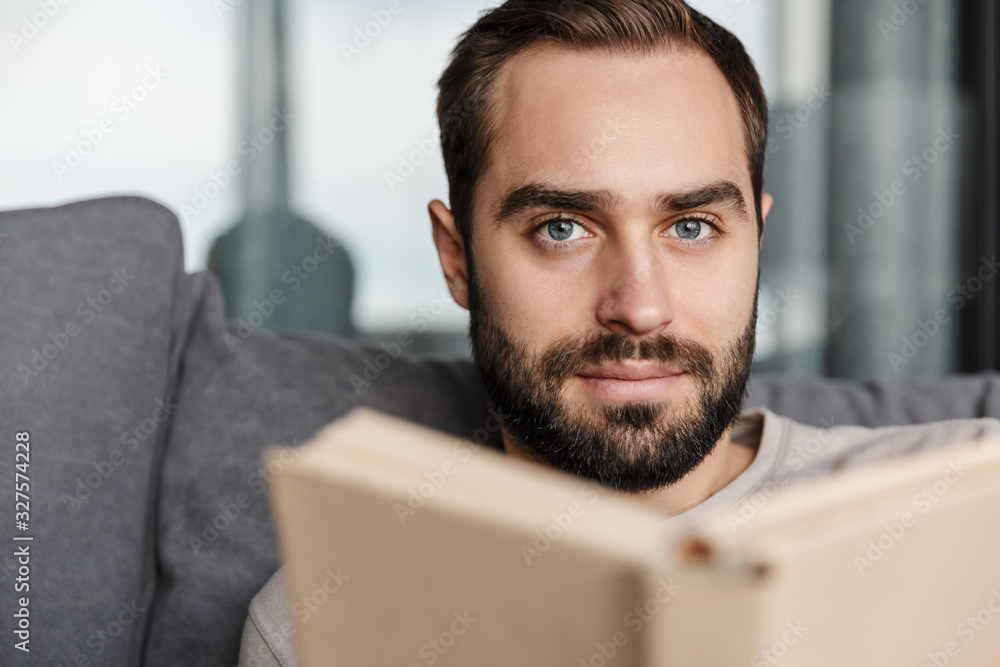 Poster Concentrated young handsome man reading book.