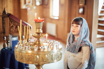 Russian girl praying in front of icons in the Orthodox Church