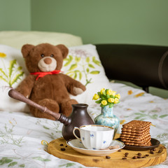 Breakfast in bed with a cezve, a cup, a vase of flowers and cookies