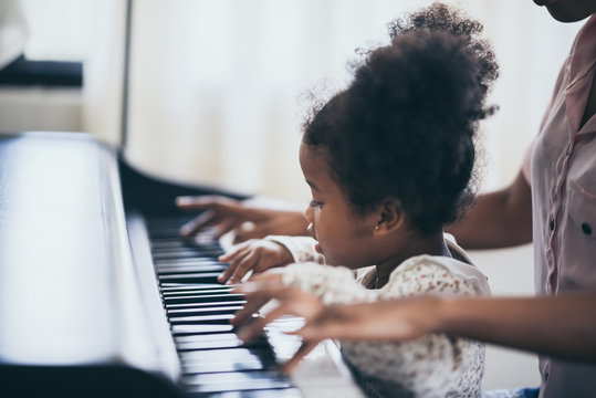 American African young pianist, teacher teaching girl kid student to play piano, Art of music education concept