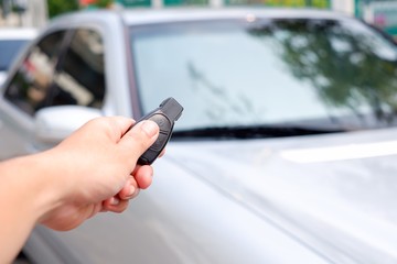 The man’s hand is holding the remote control and then use the new push button to open the car door. Conceptual technology equipment for vehicles.