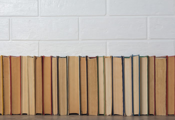 A stack of old books. Bookstore, library, bookshelf. Vintage, retro, antique. Study, education, school, University. Literature, history, science. Books against a white brick wall.
