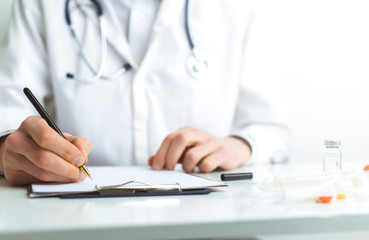 Doctor writes a diagnosis while working in the office.
