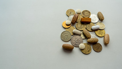 Pills mixed with coin on a light background. Medical concept.