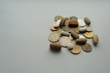 Pills mixed with coin on a light background. Medical concept