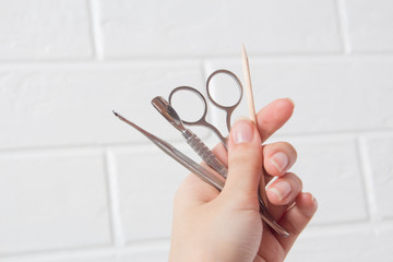 Hold manicure tools in your hand. Nail care, procedure, nail salon. Tweezers, wire cutters, pusher,...
