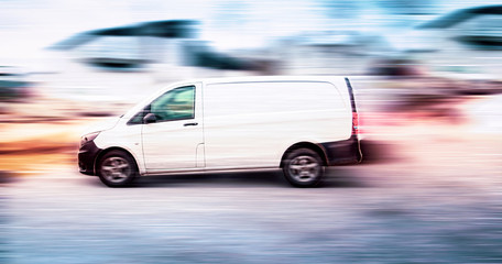 Plakat White delivery van speeding on road with blurred background.