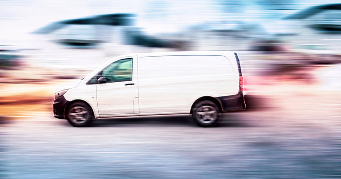 White delivery van speeding on road with blurred background.