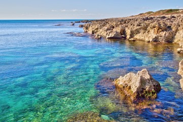 Fototapeta na wymiar Rocky coastline and turquoise transparent sea in the Salento coast near Taranto, Puglia, Italy
