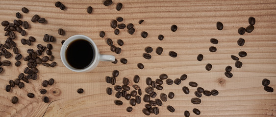 Cup with black coffee on wooden board with beautiful grain and represented coffee beans