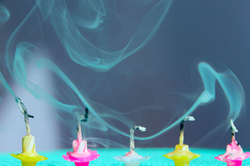 Blurred image of fading candles, blurry smoke, blue background. Holidays, Birthday concept. Small...