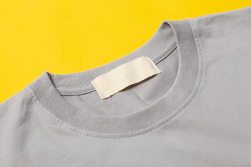 Blank tag of grey t-shirt for your design isolated on yellow background.