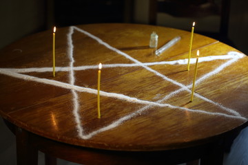 Men's hands set candles on the pentagram symbol