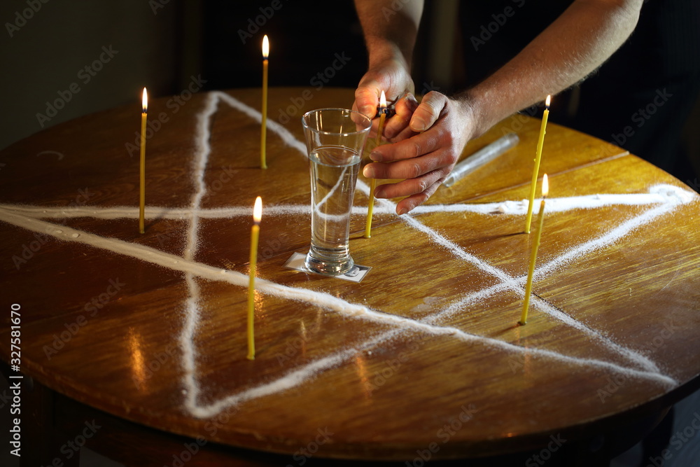 Wall mural Men's hands set candles on the pentagram symbol