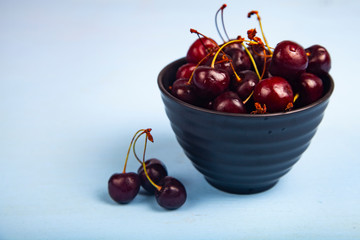 Ripe sweet cherry in a black bowl