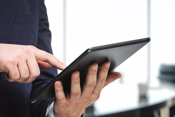 Man using digital tablet in bright sunny office, close up. Technology concept