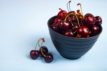 Ripe sweet cherry in a black bowl