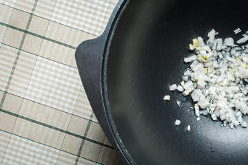 Sliced white onions in oil for frying in cast iron cauldron for pilaf.