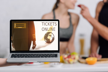 selective focus of laptop with tickets online website on screen near couple in kitchen