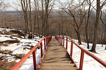 Plakat Narrow wooden stepped path leading from the hill down to the river on a sunny winter day