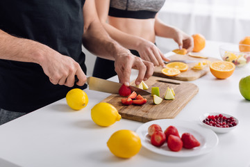 cropped view of man and woman preparing fruit salad