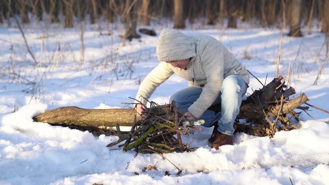 A man kindles a fire lighter in the winter forest