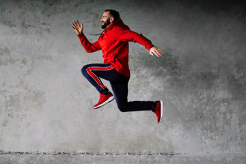 Obraz premium Attractive sportsman running against grey wall.
