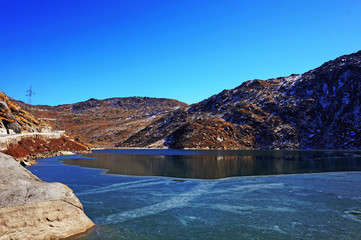 Under the nice blue sky covered with thin ice the Tsomgo Lake or Changu Lake water surrounded by stone mountains